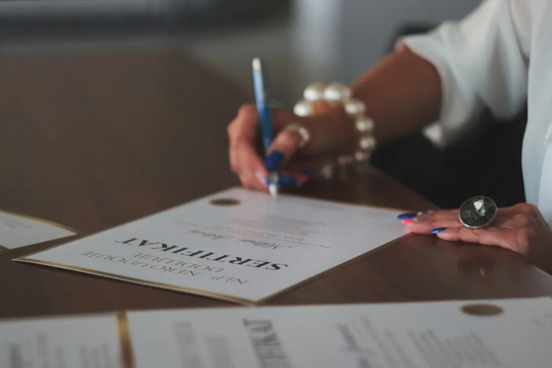 Person signing a certificate at a table.