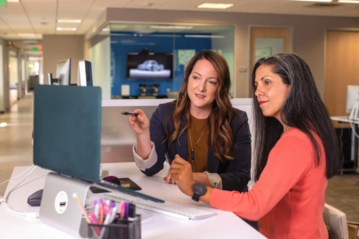 Two women collaborating at a computer in an office.